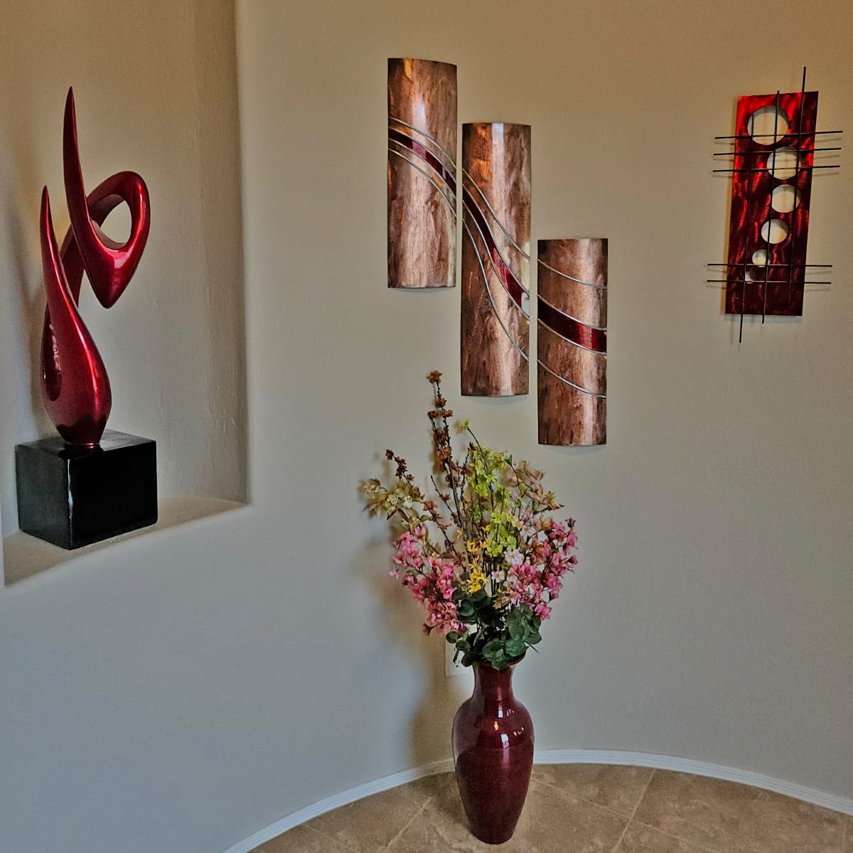 Meyerdirk Art grouped in an interior: red sculpture, copper triptych, and a circular wall piece